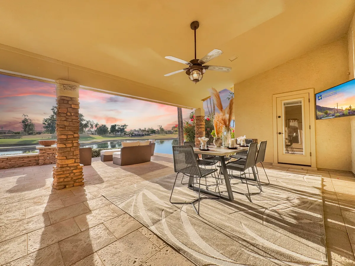 A stylish outdoor patio with a dining table set for al fresco meals and comfortable seating, overlooking a beautiful landscape beyond. The scene invites relaxation, socializing, and enjoyment of the outdoors, suggesting an elegant transition from the golf course to home.