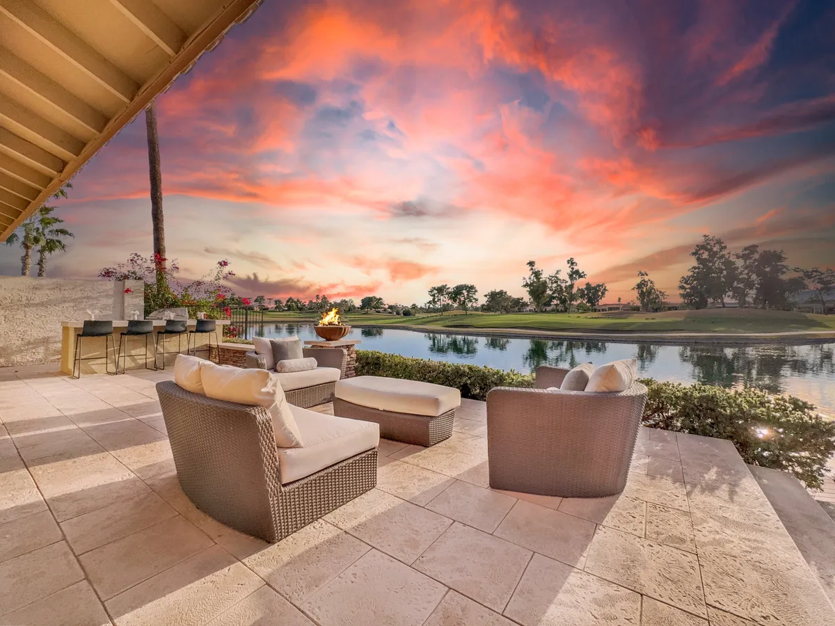 A cozy outdoor seating area positioned to take in a vibrant sunset sky over the lake. The setup is inviting for intimate gatherings, leisurely conversations, or simply soaking in breathtaking sunset views.