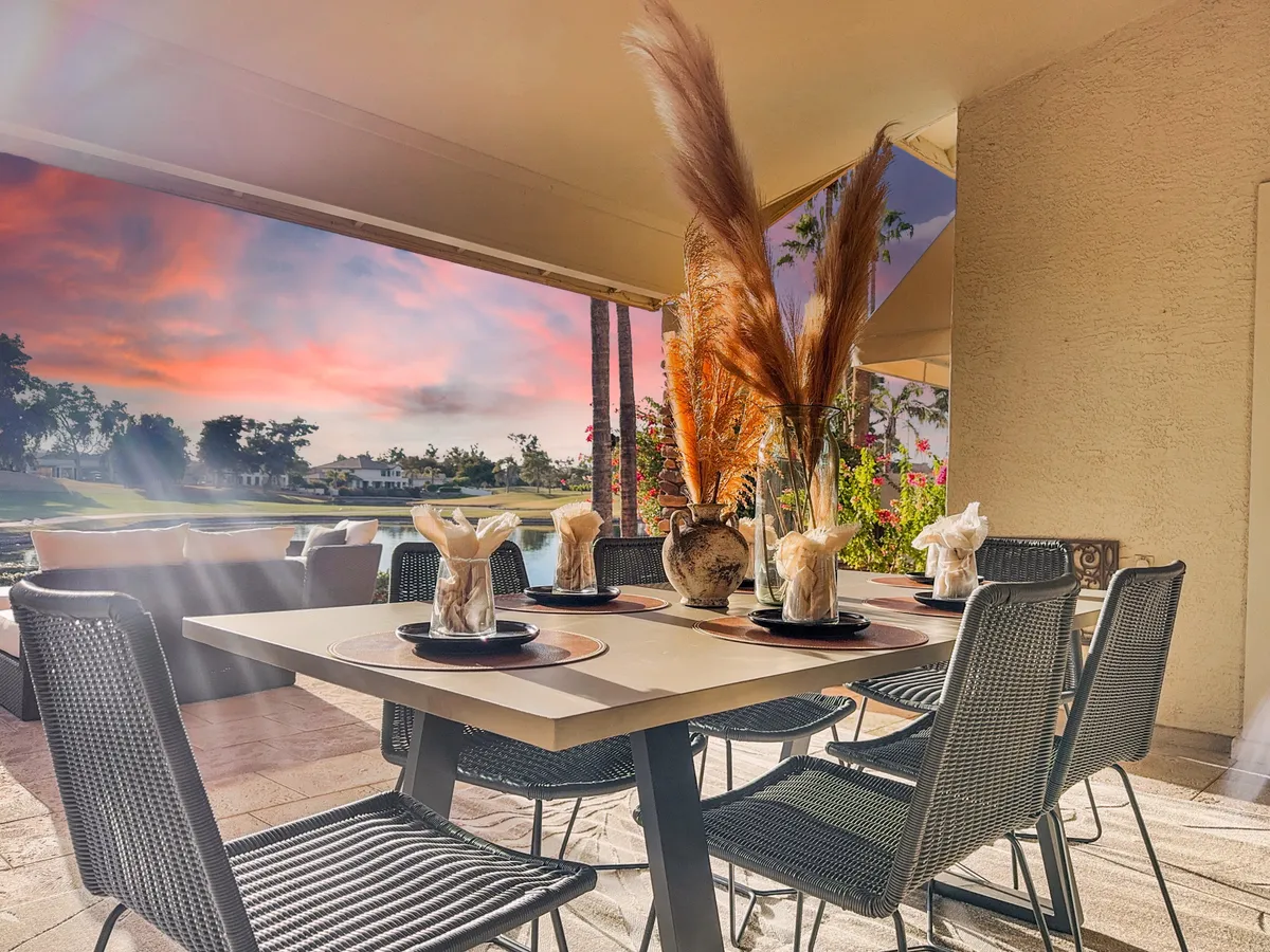 A stylish outdoor dining setup with a decorative vase, elegant dinnerware, and comfortable seating, all bathed in warm natural light. The scene is set for sunset dining or relaxed entertaining, with an atmosphere that blends sophistication and comfort.