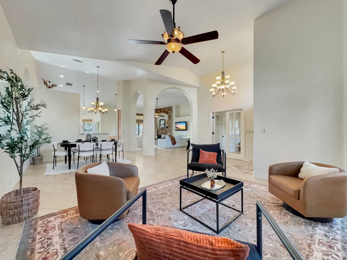 An inviting interior space with a comfortable seating area, a large dining table, decorative lighting, and expansive windows that flood the room with natural light. The arrangement is ideal for hosting small events or social gatherings.