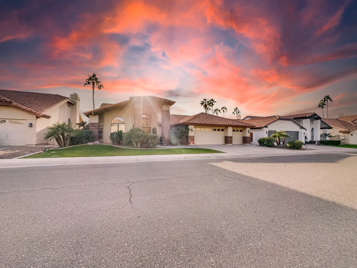 A welcoming exterior shot of the house features a prominent entrance framed by lush greenery and set against a vibrant sky, suggesting a lively yet peaceful atmosphere. The front yard is well-landscaped, inviting residents and visitors alike to gather outdoors or simply enjoy an evening stroll.
